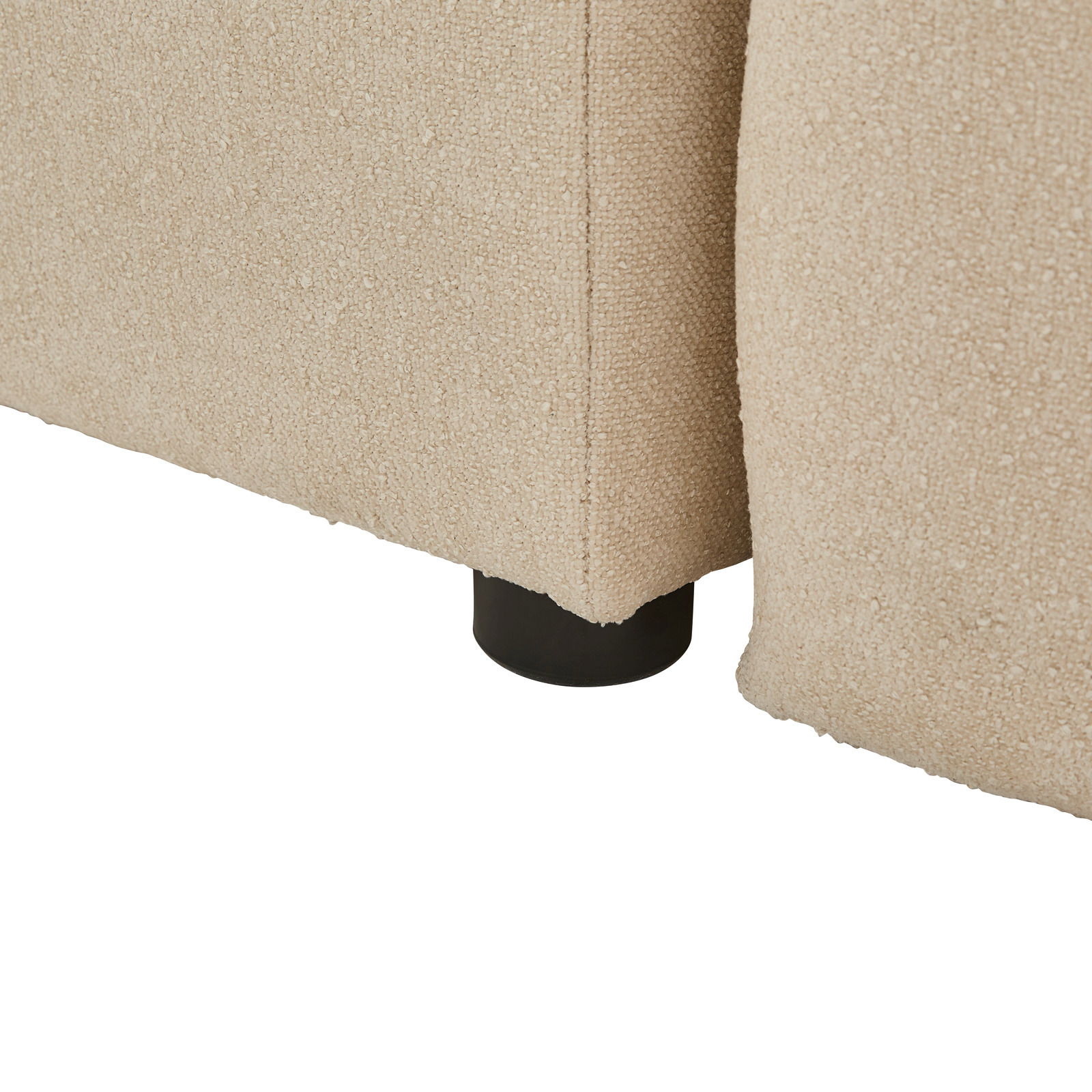 Nahaufnahme der Ecke eines beige gepolsterten Boxbetts mit schwarzem Fuß, seitliche Perspektive