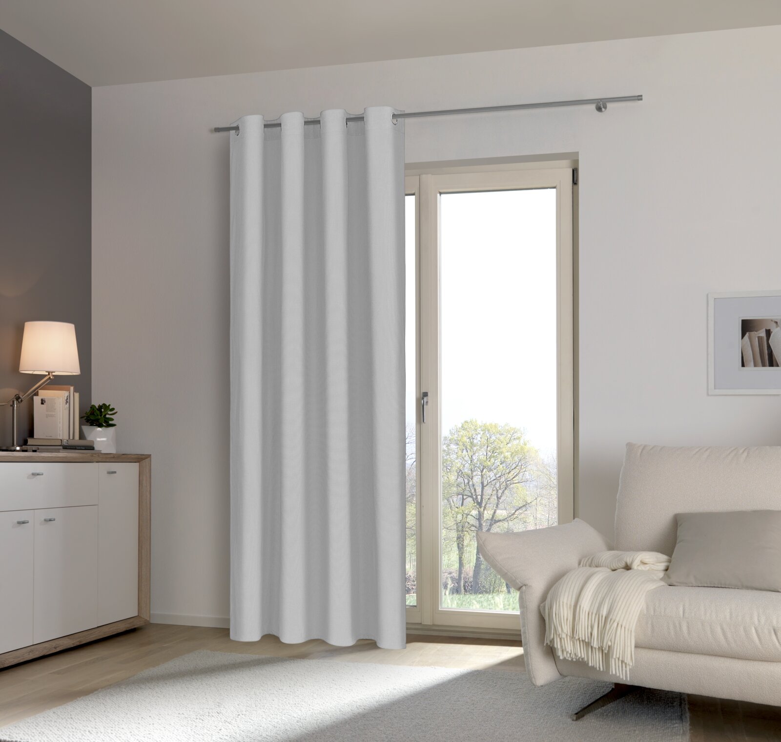 Esposa Ösenschal 135x245cm Moderner Wohnraum mit weißem Ösenschal vor einer Terrassentür, seitliche Perspektive