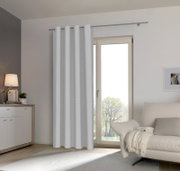 Moderne woonkamer met een witte sjaal met oogjes voor een terrasdeur, zijaanzicht