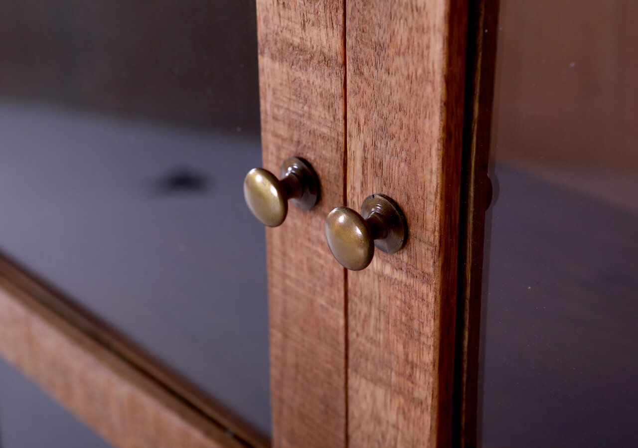 Nahaufnahme einer Vitrine mit Holzrahmen und zwei runden Metallgriffen, seitliche Perspektive.
