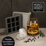 Flexible Eiswürfelform aus Silikon, perspektivisch von vorne gezeigt, mit einem Glas Whisky und Eiswürfeln daneben.