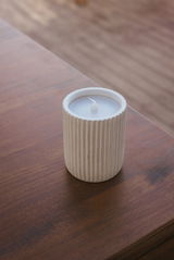 Outdoor-Kerze in einem geriffelten, weißen Behälter auf einem Holztisch aus der Vogelperspektive