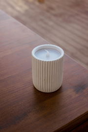 Outdoor-Kerze in einem geriffelten, weißen Behälter auf einem Holztisch aus der Vogelperspektive