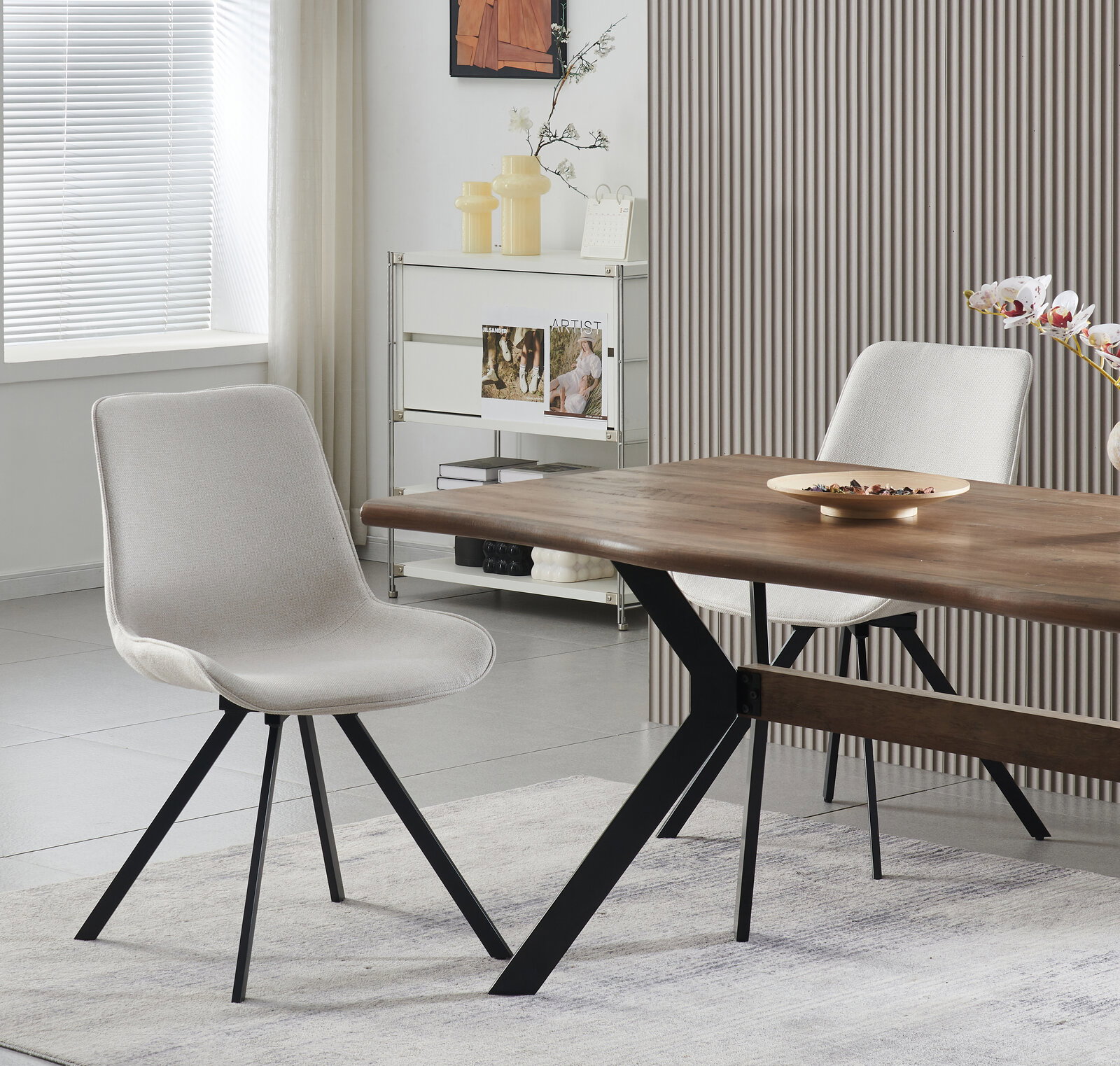 Moderner Esszimmerstuhl in hellgrauem Stoffbezug mit schwarzem Metallgestell, seitliche Perspektive im Esszimmer neben Holztisch