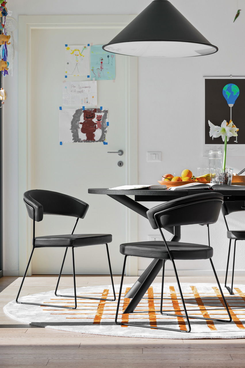 Moderner schwarzer Stuhl mit Metallbeinen, seitliche Perspektive, in einem Esszimmer mit Tisch und Dekorationen.