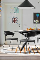 Moderner schwarzer Stuhl mit Metallbeinen, seitliche Perspektive, in einem Esszimmer mit Tisch und Dekorationen.