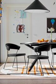 Moderner schwarzer Stuhl mit Metallbeinen, seitliche Perspektive, in einem Esszimmer mit Tisch und Dekorationen.