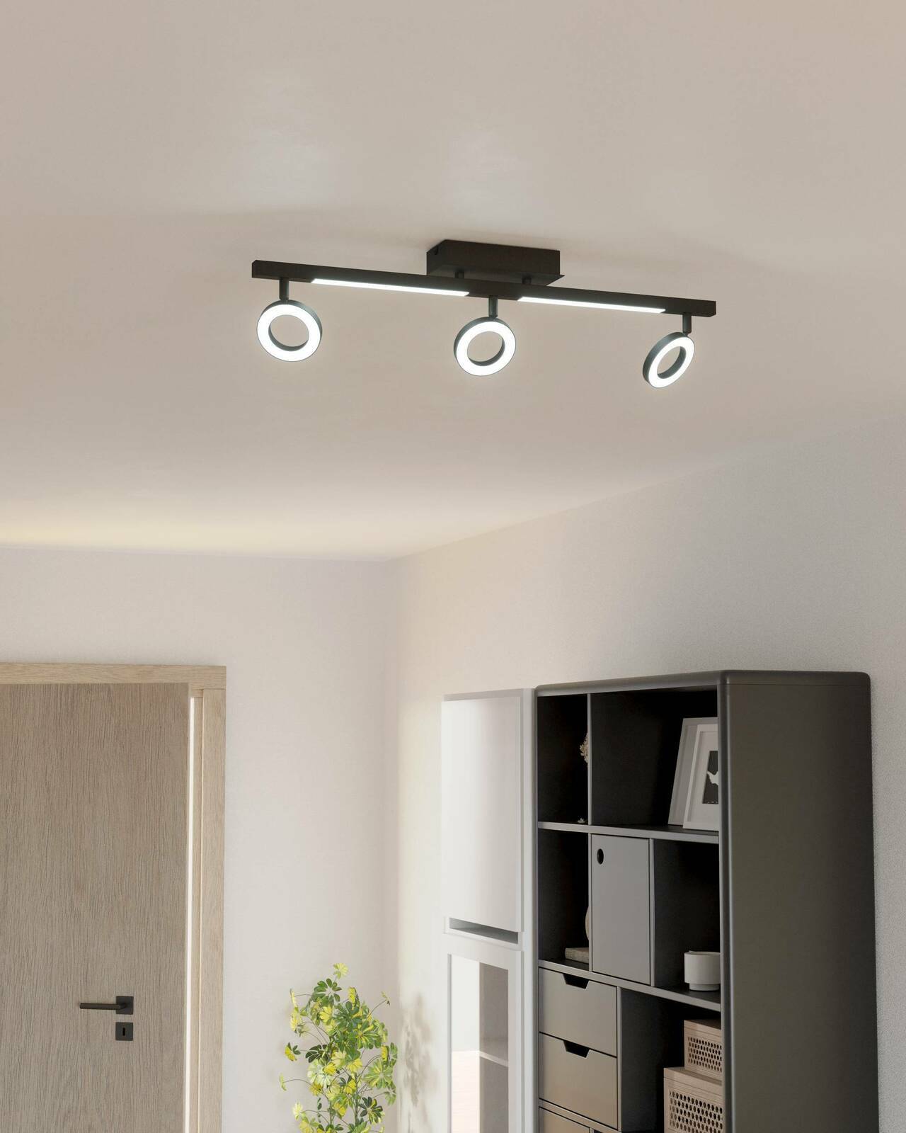 Moderne Deckenleuchte mit drei verstellbaren Spots in einem hellen Raum, seitliche Perspektive