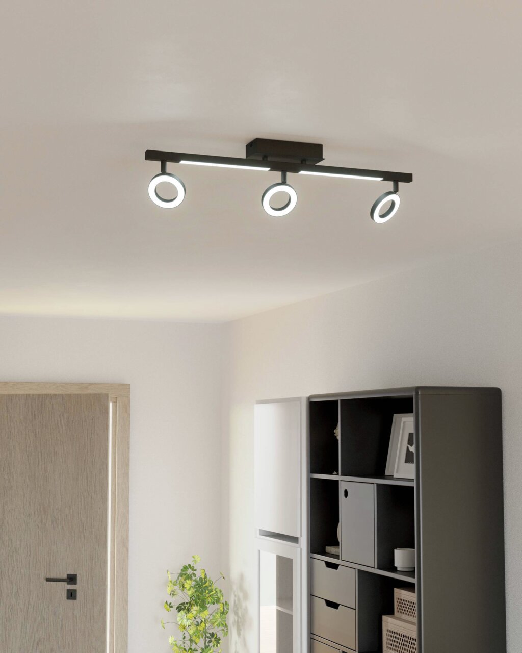 Moderne Deckenleuchte mit drei verstellbaren Spots in einem hellen Raum, seitliche Perspektive