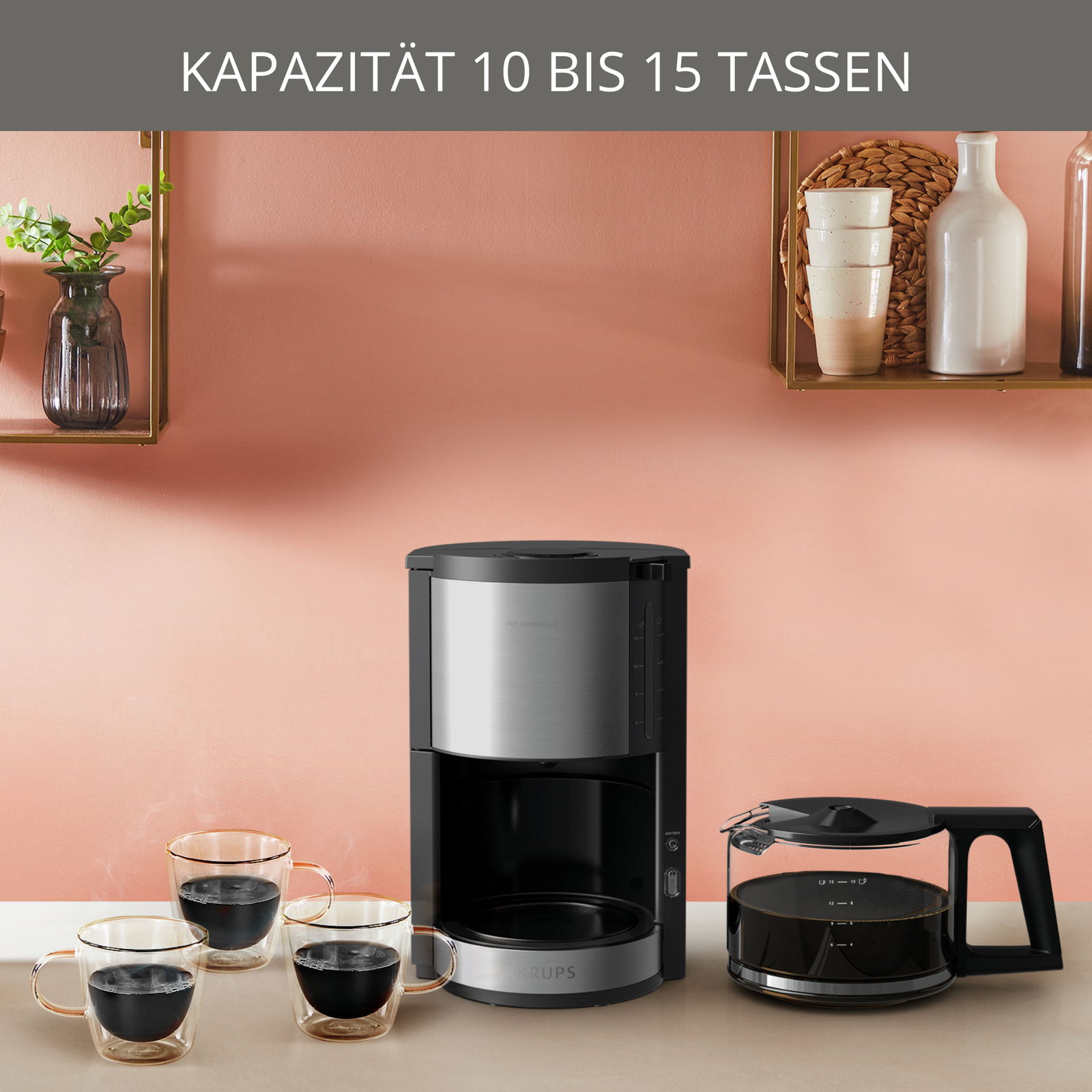Kaffeemaschine ProAroma Plus in einer modernen Küche, frontal abgebildet, mit drei gefüllten Kaffeetassen und einer Glaskanne daneben. Kapazität 10 bis 15 Tassen.