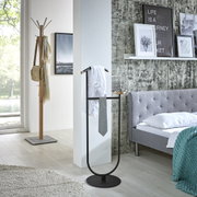 Schwarzer Kleiderständer/Butler mit rundem Standfuß, Holzdetails und Ablage, mit Hemd und Krawatte im Schlafzimmer neben grauem Bett, Perspektive: leicht seitliche Frontansicht
