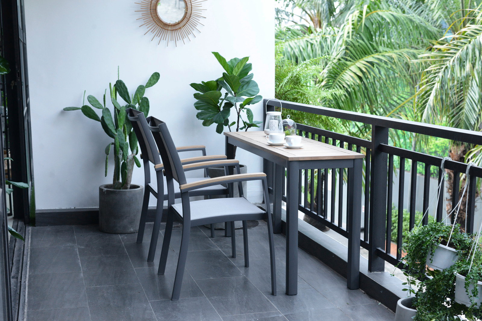 Moderner Beistelltisch auf einem Balkon, umgeben von Pflanzen, mit zwei Stühlen und einer Tasse Kaffee, seitliche Perspektive.