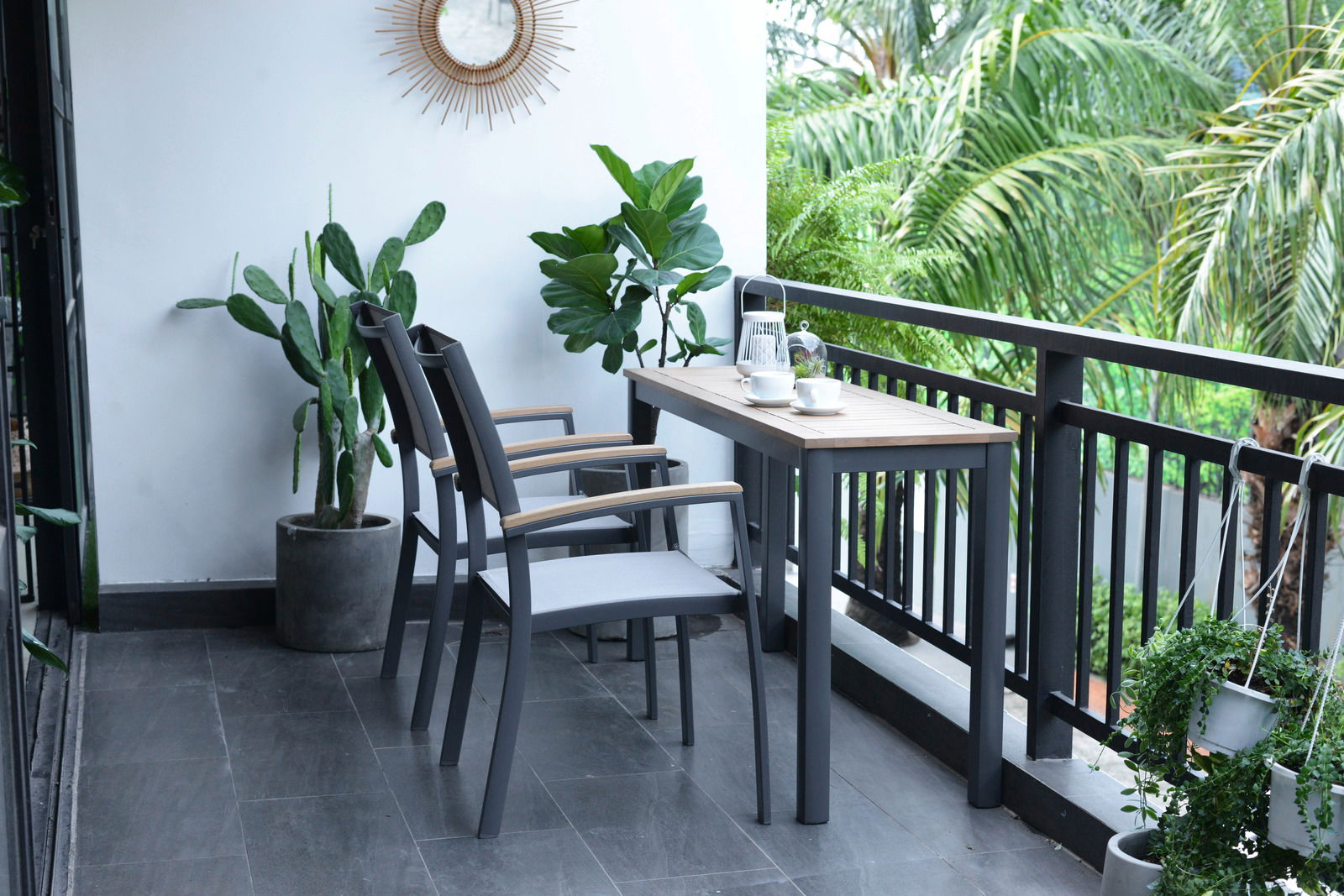 Moderner Beistelltisch auf einem Balkon, umgeben von Pflanzen, mit zwei Stühlen und einer Tasse Kaffee, seitliche Perspektive.