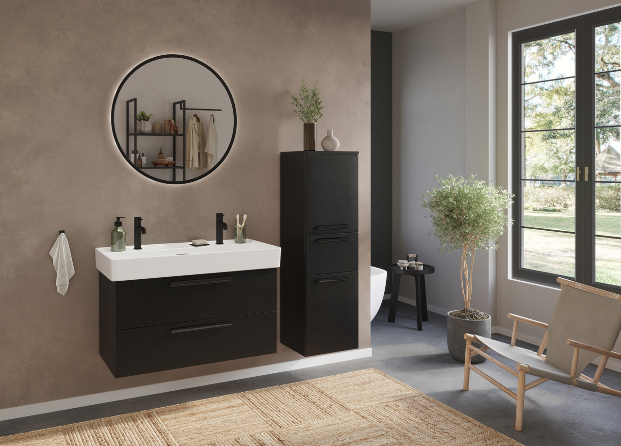 Modernes Badezimmer mit Waschtisch-Set für zwei Armaturen, schwarzem Unterschrank und rundem Spiegel, seitliche Perspektive.