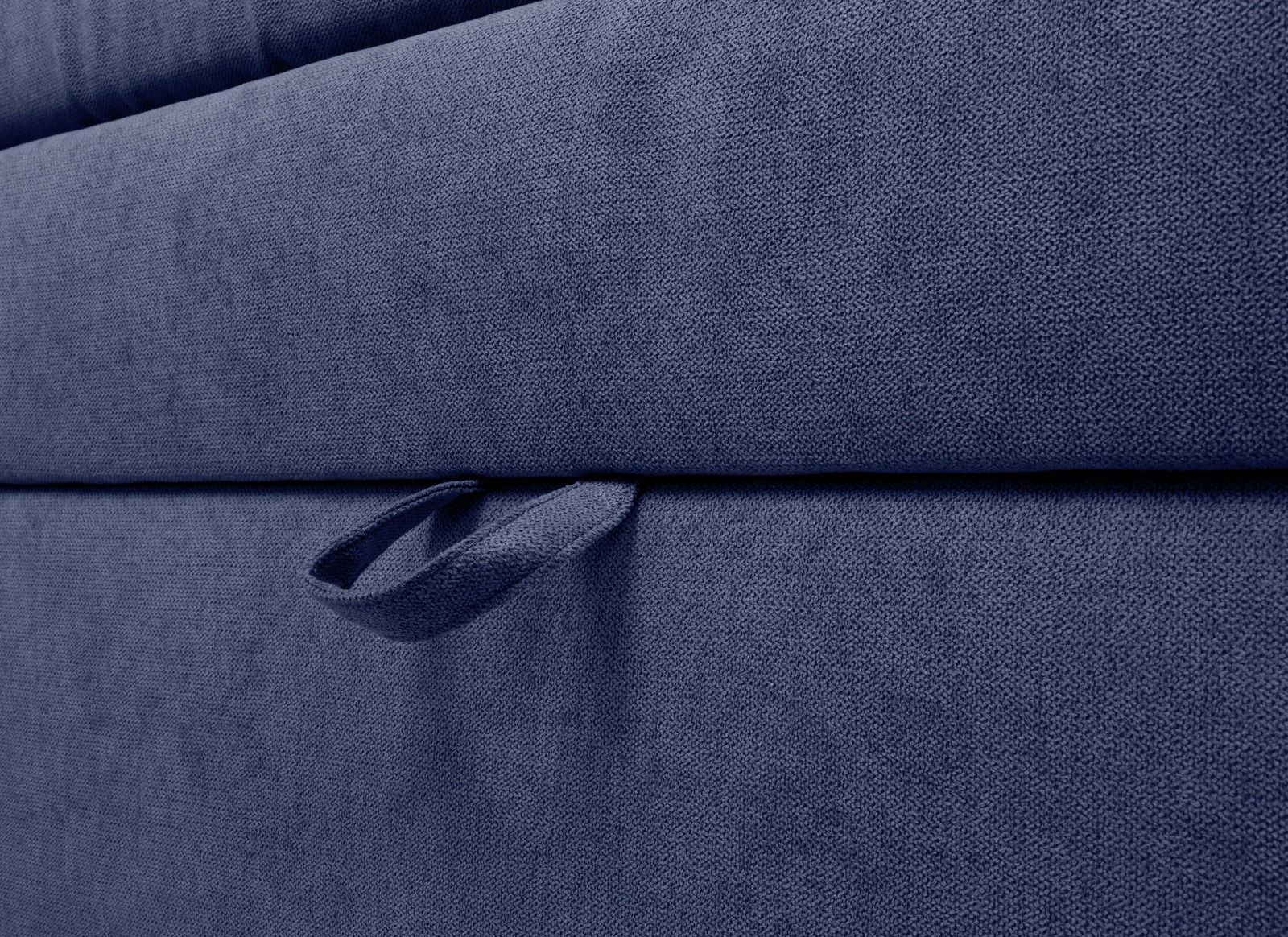 Nahaufnahme eines blauen Boxspringbetts mit Stoffbezug und Griff, seitliche Perspektive