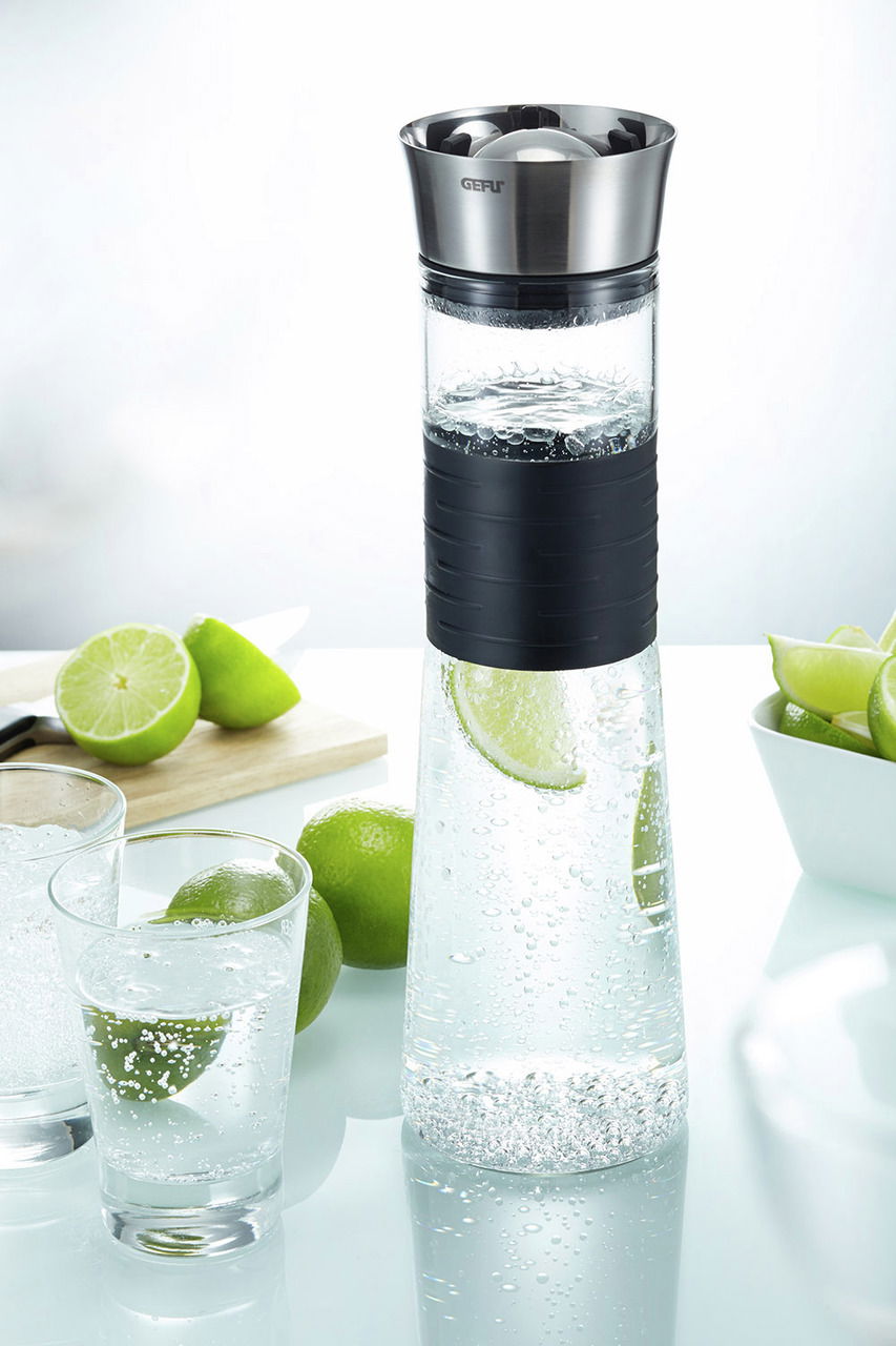 Karaffe 1l CASCADA mit Edelstahlverschluss und schwarzem Griff, gefüllt mit sprudelndem Wasser und Limettenscheiben, aus seitlicher Perspektive fotografiert.