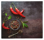 Herdabdeckplatte mit roten Chilischoten, Pfefferkörnern und grünen Blättern aus der Vogelperspektive