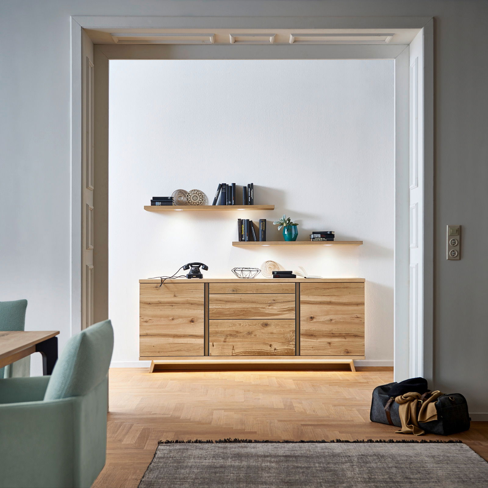 Holz-Sideboard in einem modernen Wohnzimmer, frontal fotografiert, mit dekorativen Regalen darüber.