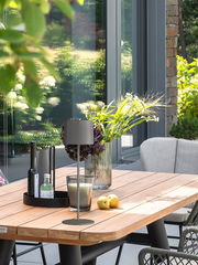 Moderne Akku-Tischleuchte SUN auf einem Holztisch in einem stilvollen Außenbereich, seitliche Perspektive.