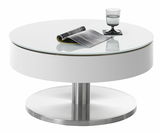 Moderner runder Couchtisch SUVA mit weißer Glasplatte und Edelstahlfuß, seitliche Perspektive, darauf ein Glas und eine Zeitschrift.