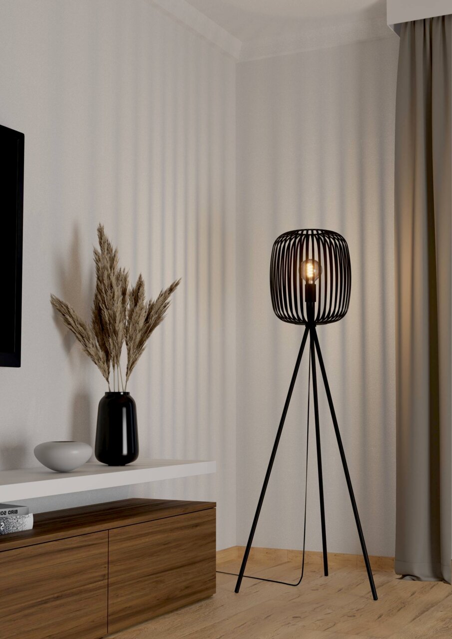 Moderne Stehleuchte ROMAZZINA mit schwarzem, dreibeinigem Gestell und offenem Lampenschirm in einem stilvollen Wohnzimmer, seitliche Perspektive.
