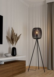 Moderne Stehleuchte ROMAZZINA mit schwarzem, dreibeinigem Gestell und offenem Lampenschirm in einem stilvollen Wohnzimmer, seitliche Perspektive.