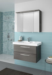 Moderner Badblock mit grauen Schubladen und weißem Waschbecken, frontal betrachtet, vor einer Wand mit blauen Fliesen.