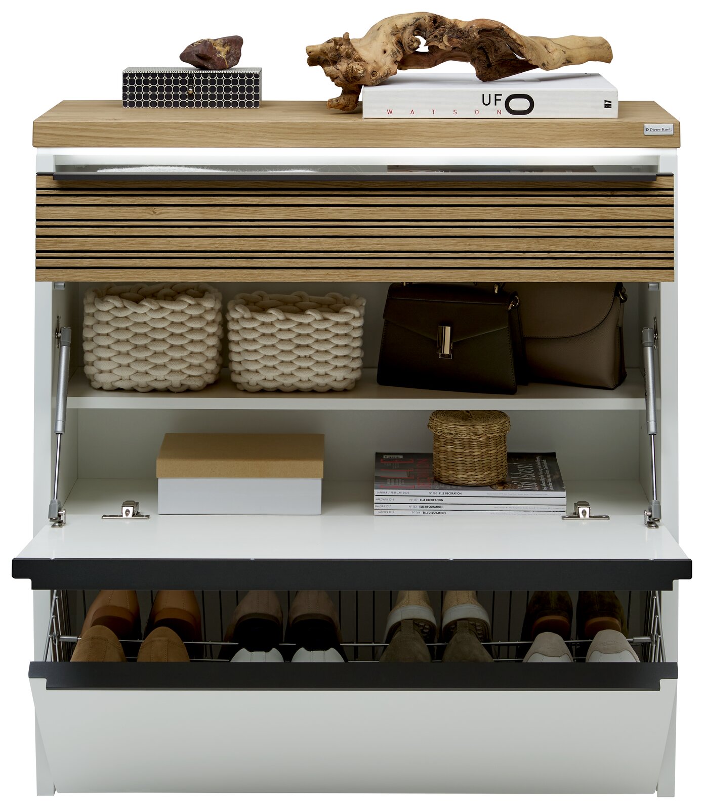 Frontansicht eines modernen weißen Schuhschranks mit Holzdeckplatte und Lamellenfront, geöffnet mit Klappfach, Ablagefächern und Schuhkorb; dekoriert mit Büchern, Körben und Taschen.