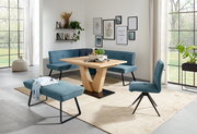 Moderne Esszimmer-Einrichtung mit blauer Eckbank, passendem Stuhl und Hockerbank, sowie einem Holztisch mit V-Gestell, aus der Perspektive des Raumes betrachtet.