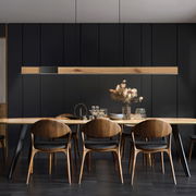 Moderne Pendelleuchte PURE-MOTO-RISE über einem Esstisch, aus Holz und Metall, in einem stilvollen Esszimmer mit dunklen Wänden, seitliche Perspektive.