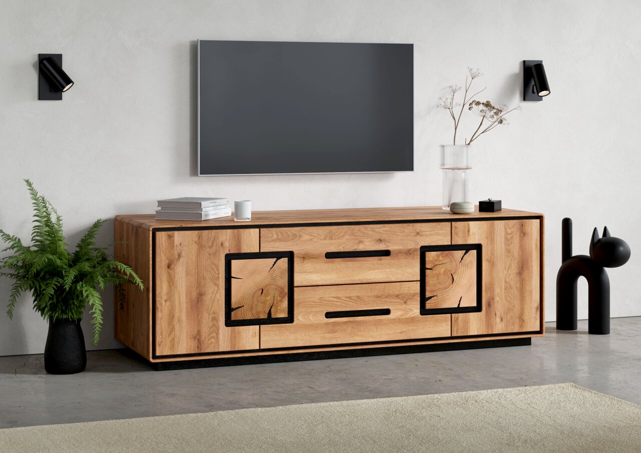 Modernes TV-Lowboard aus massiv wirkendem Holz mit schwarzem Rahmen und Griffen, frontale Perspektive im Wohnzimmer unter einem wandmontierten Fernseher.
