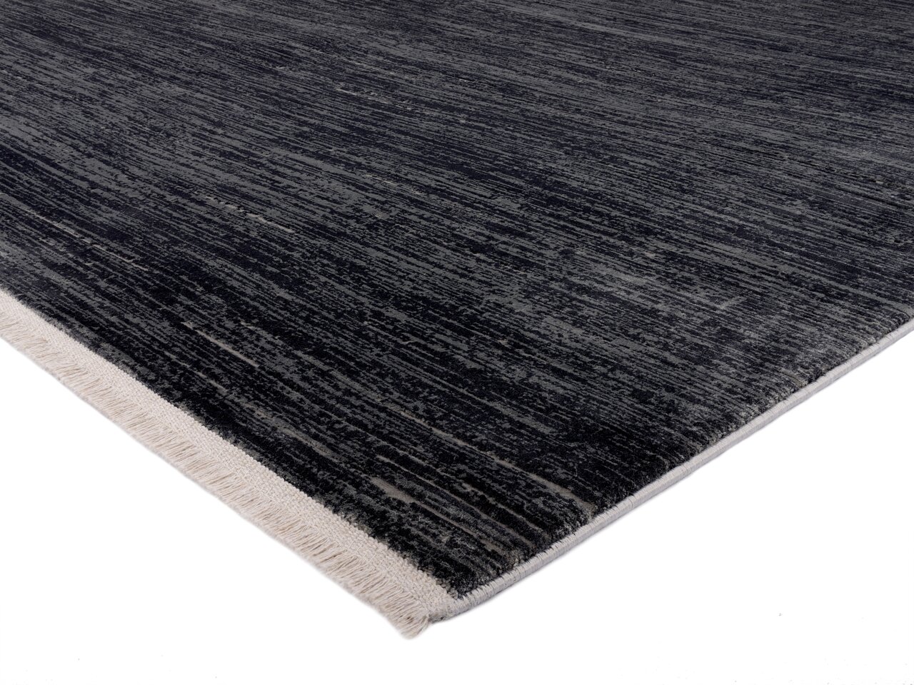 Designer Teppich in dunklen Grautönen mit heller Kante, perspektivisch von der Seite aufgenommen.