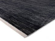 Designer Teppich in dunklen Grautönen mit heller Kante, perspektivisch von der Seite aufgenommen.