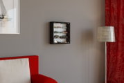 Schwarze, wandmontierte Vitrine mit Glas-Schiebetüren und mehreren Fächern für Modellautos, in Frontalansicht an einer grauen Wand im Wohnzimmer