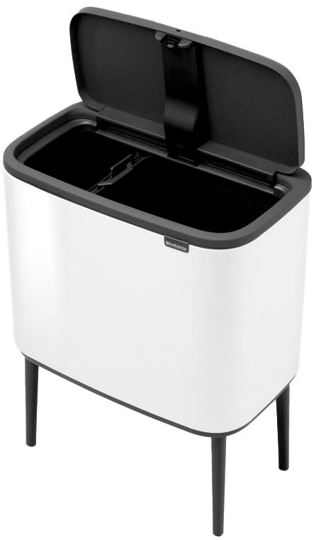 Moderner weißer Abfalleimer mit schwarzem Deckel, geöffnet, auf vier Beinen stehend, aus leicht erhöhter Perspektive.