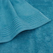 Nahaufnahme eines türkisfarbenen Handtuchs mit dekorativen Streifen am Rand, liegend auf einem weiteren Handtuch in derselben Farbe.