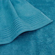 Nahaufnahme eines türkisfarbenen Handtuchs mit dekorativen Streifen am Rand, liegend auf einem weiteren Handtuch in derselben Farbe.