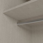 Detailaanzicht van onderaf van een metalen kledingroede onder een legplank in een lichtgekleurde kledingkast