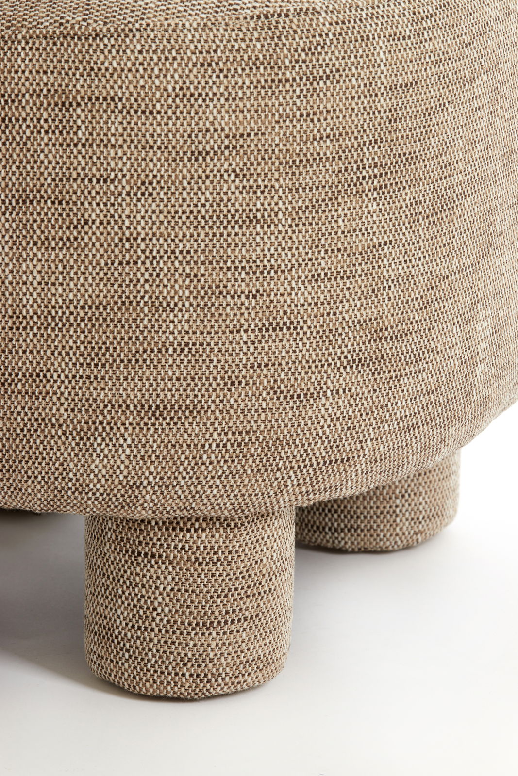 Nahaufnahme eines Sessels mit beigem, strukturiertem Stoffbezug und runden Beinen, seitliche Perspektive