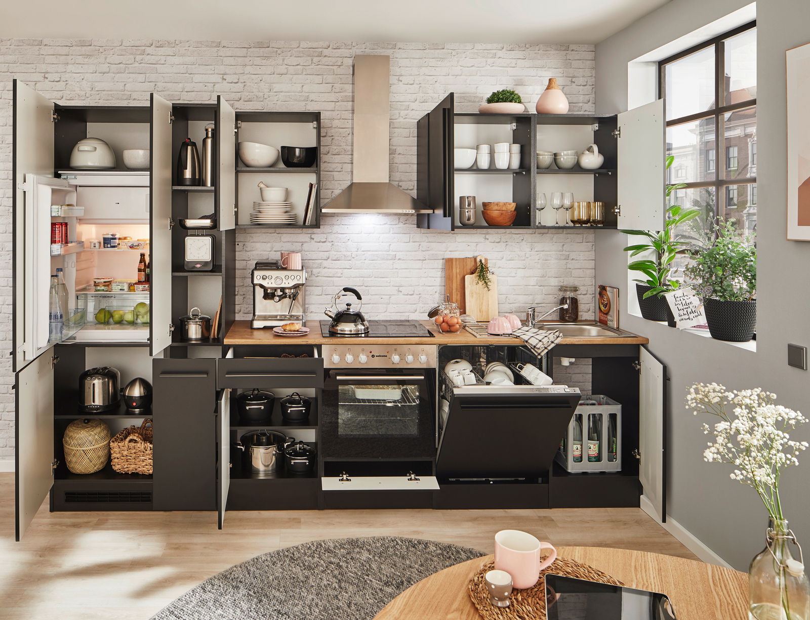 Moderne Küchenzeile in dunklem Design mit offenen Schränken, Kühlschrank, Herd und Spüle, fotografiert aus frontaler Perspektive.