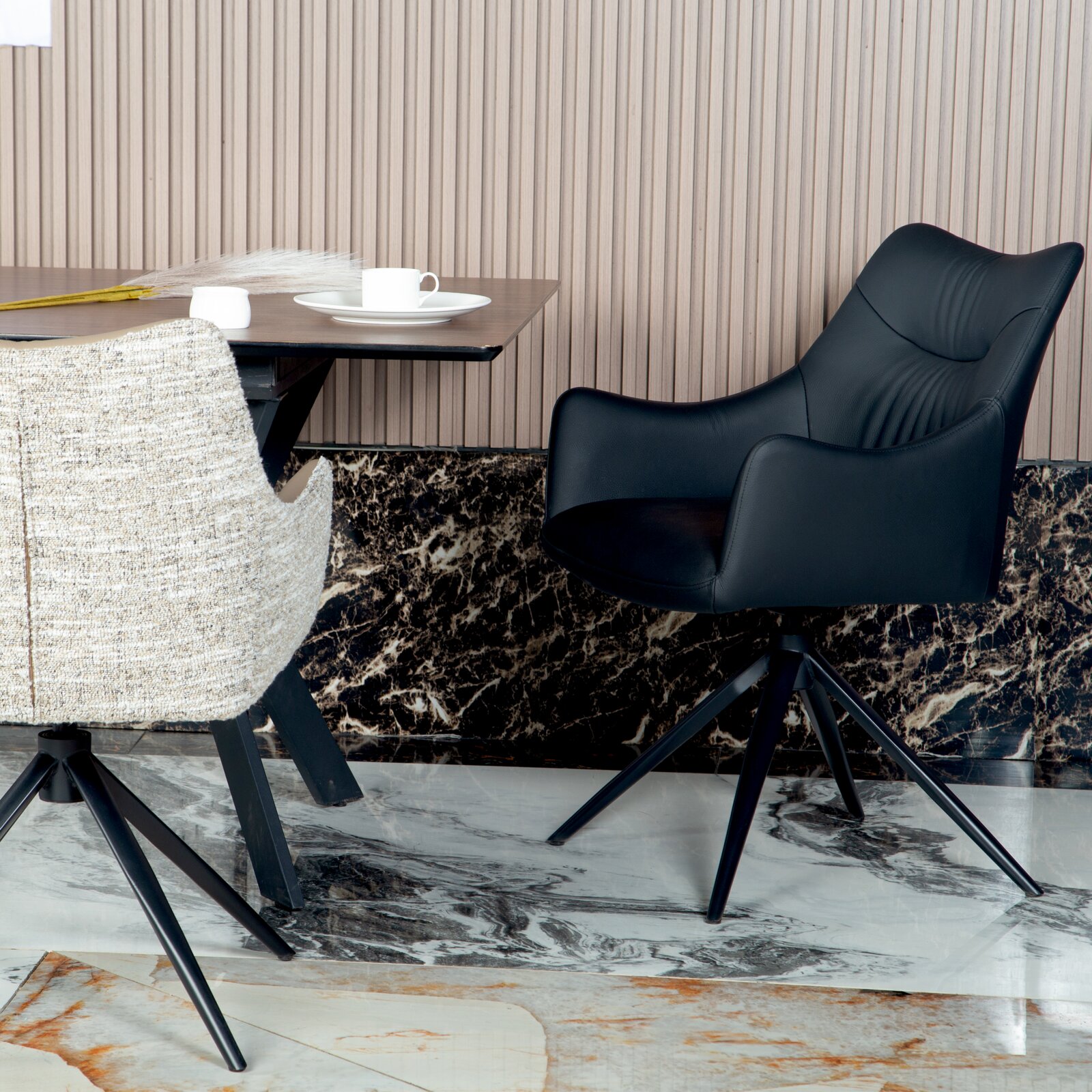 Novel Fauteuil BELFORT Zwarte fauteuil met een modern ontwerp, gezien vanaf de zijkant, naast een tafel met een kopje.