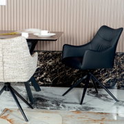 Zwarte fauteuil met een modern ontwerp, gezien vanaf de zijkant, naast een tafel met een kopje.