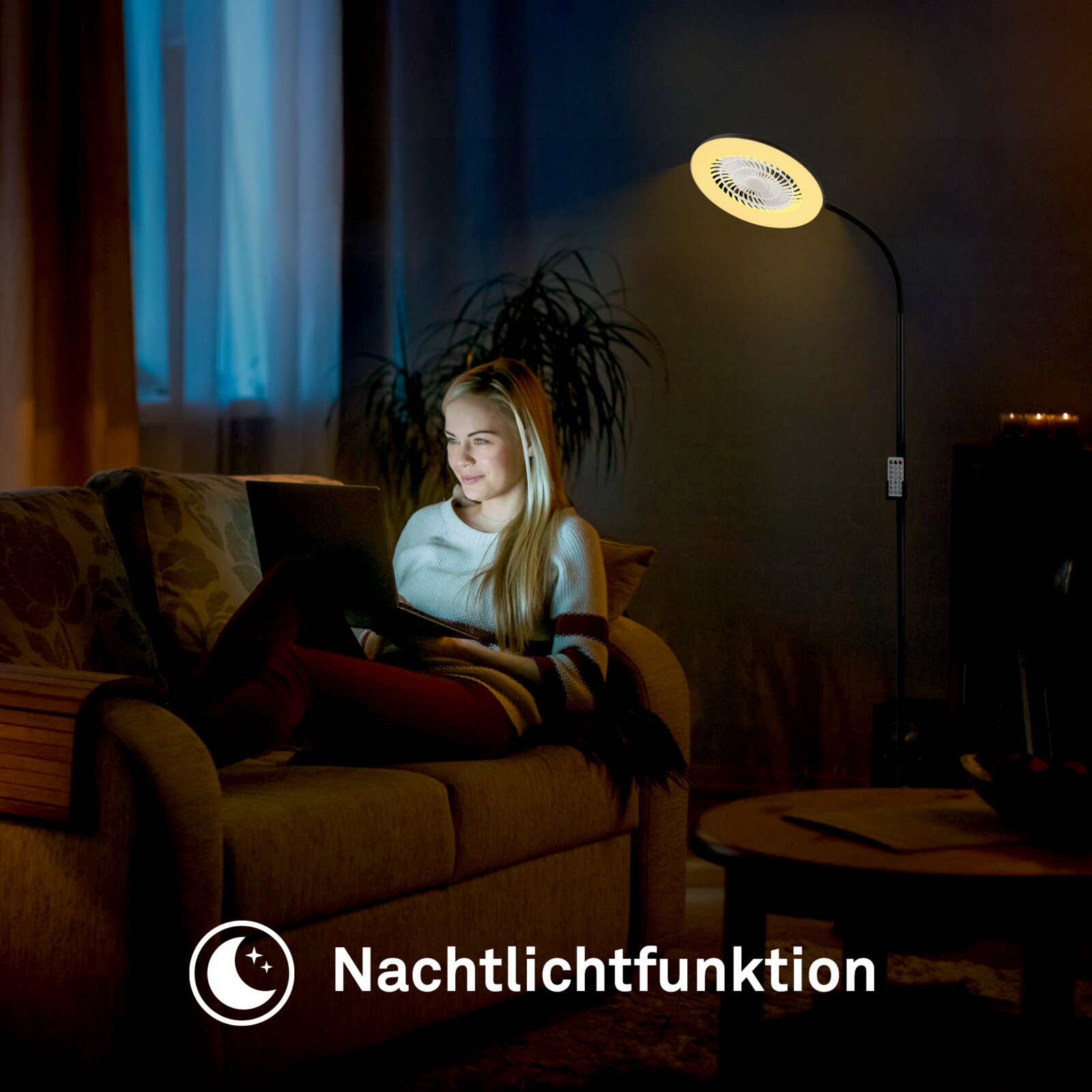 Schwarze LED-Stehlampe mit rundem Leuchtenkopf und warmem Nachtlicht, seitliche Ansicht im Wohnzimmer neben einem Sofa