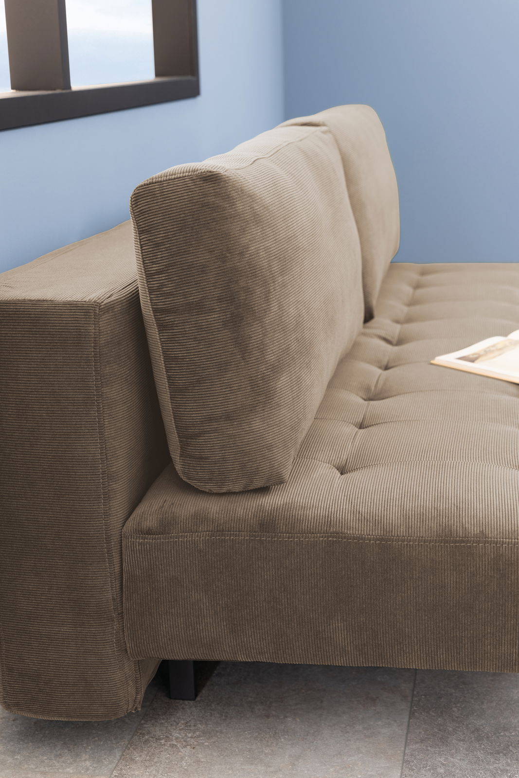 Nahaufnahme eines braunen Funktionssofas mit geripptem Stoffbezug, seitliche Perspektive.