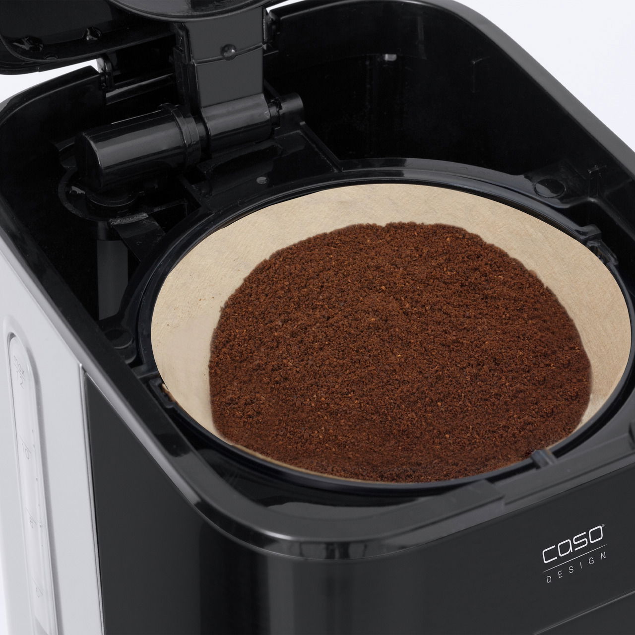 Nahaufnahme einer Filterkaffeemaschine mit geöffnetem Filterhalter, gefüllt mit Kaffeepulver.
