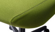 Nahaufnahme eines grünen Drehstuhlsitzes mit Textilbezug, seitliche Perspektive