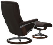 Rückansicht eines braunen Einzelsessels mit passendem Hocker, beide mit modernem Metall- und Holzgestell.