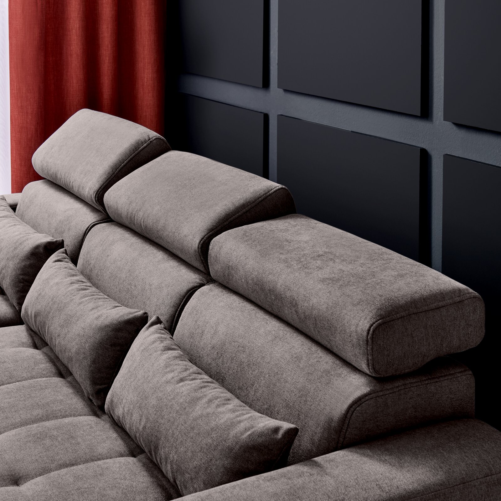 Graues Sofa mit verstellbaren Kopfstützen und Kissen, seitliche Perspektive