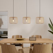 Drei moderne Pendelleuchten mit zylindrischem, goldfarbenem Gitter-Lampenschirm über einem Holzesstisch, Frontalansicht auf die Leuchten im Essbereich