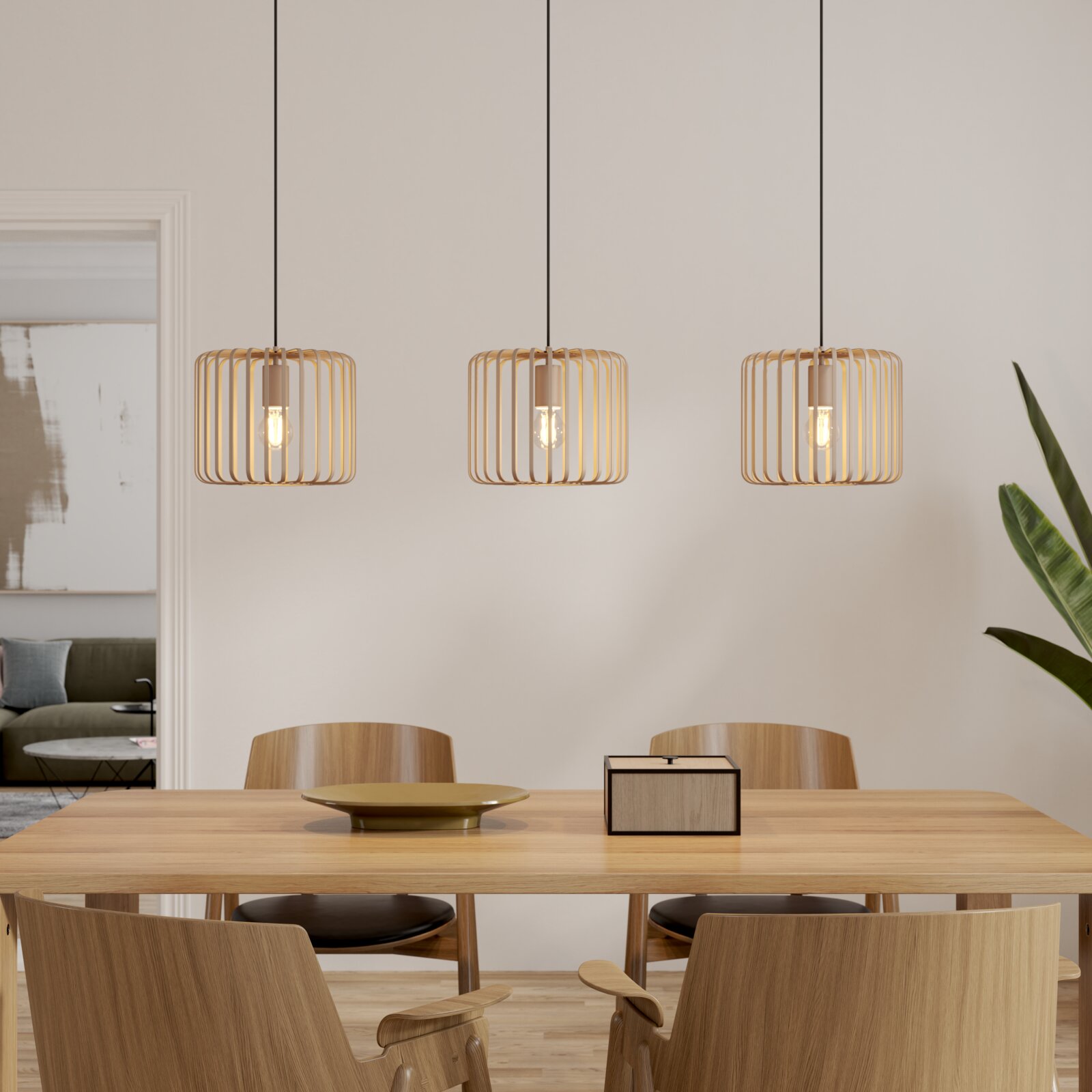 Novel Hanglamp KORRES Drie moderne hanglampen met een cilindervormige, goudkleurige roosterkap boven een houten tafel; vooraanzicht van de lampen in de eethoek